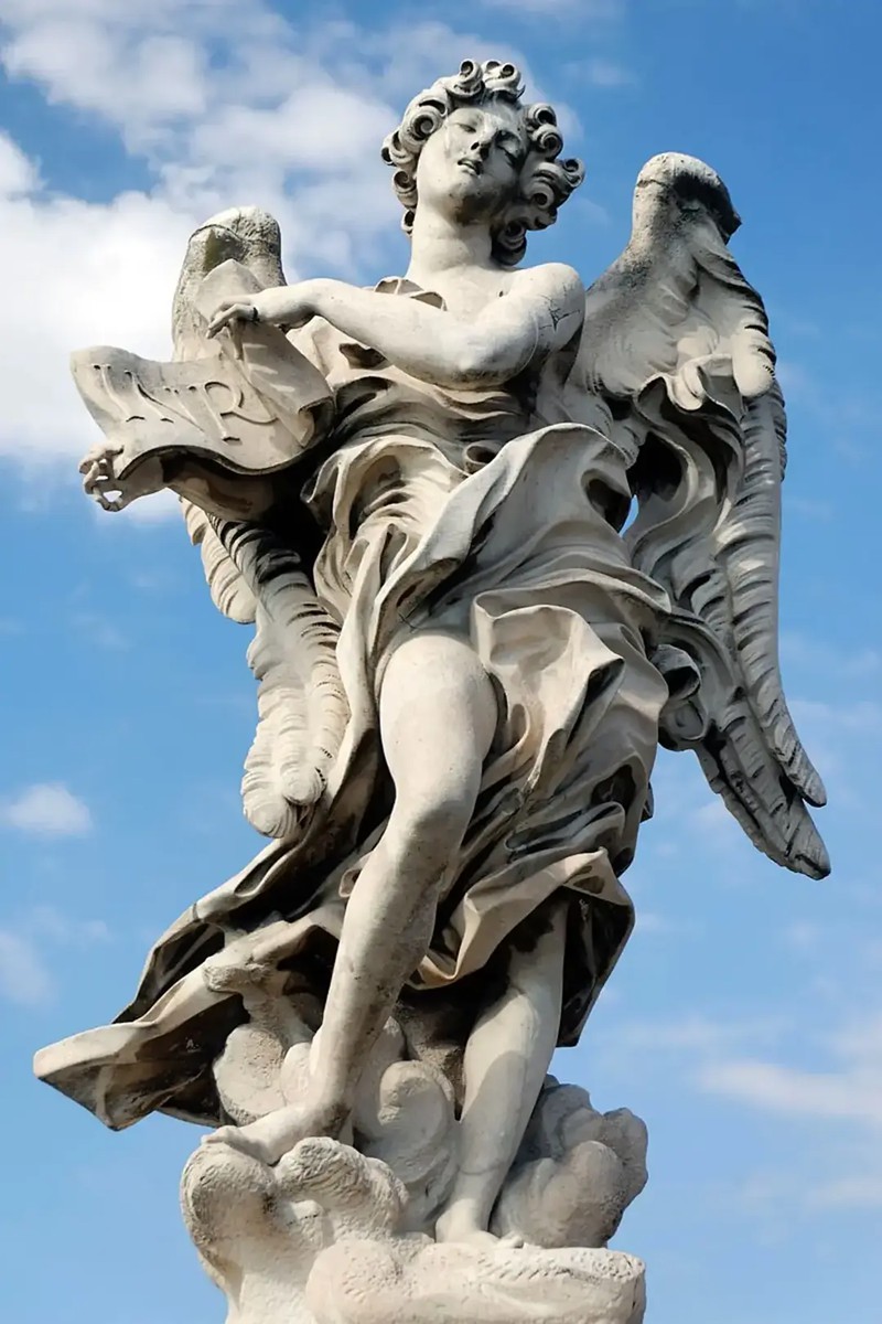 the second of benini's angels, holding a sign that reads “inri”