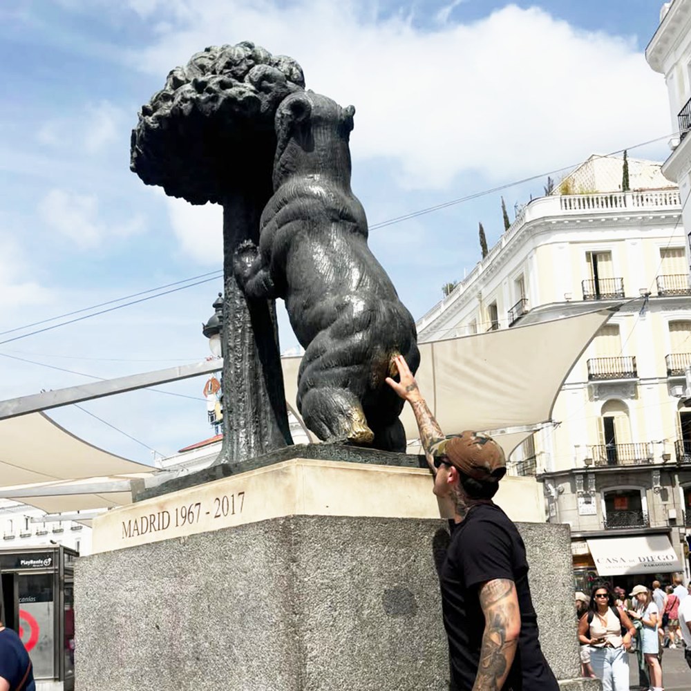 Tourist touching the lucky bronze bear statue in Madrid for good luck